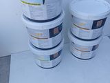 several buckets of paint sitting on top of a table next to a wall