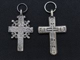 two silver crosses are shown on a black surface