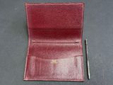 a red leather wallet with a pen sitting on top of it