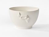 a white bowl with a bird on it on a white surface