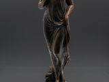 une statue en bronze d'une femme tenant un oiseau sur un piédestal