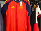 many soccer shirts hanging on a rack in a room