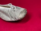 pair of silver shoes on a red surface with a red background