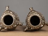 two silver vases that are sitting on a table