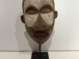 an image of a wooden mask on a stand with a white background