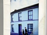 une photo d'un homme et d'une femme debout devant une maison bleue