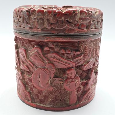 une boîte rouge ornée de sculptures, posée sur une surface blanche