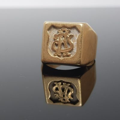 une image représentant une bague en or ornée d'un blason et d'une couronne