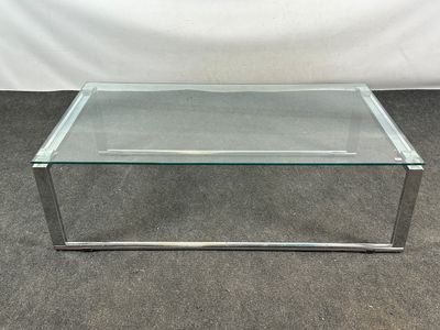 une table basse en verre avec des pieds chromés et un plateau en verre