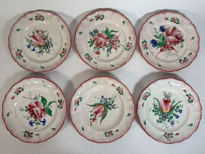 six plates with floral designs on them sitting on a white surface