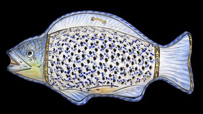 a blue and white fish shaped dish on a black background