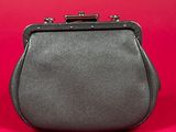 a close up of a black purse on a red background