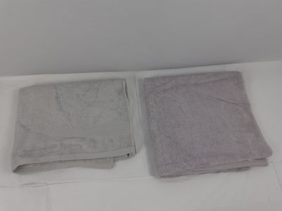 deux serviettes posées sur un lit dans une chambre aux murs blancs