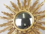 a gold sunburst mirror hanging on the wall