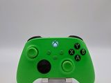a close up of a green xbox controller on a white surface