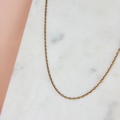 un collier à chaîne en or posé sur une surface en marbre