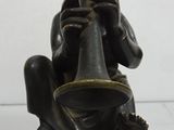 a statue of a man sitting on a stool playing a flute