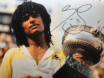 photo dédicacée d'un joueur de tennis tenant un trophée devant un public