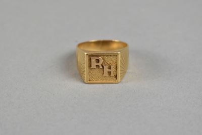 a gold signet ring with the letter rh on it