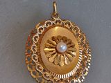 une image représentant un pendentif en or orné d'une perle au centre