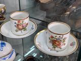many cups and saucers on display in a glass case