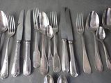 a lot of silver spoons and forks laid out on a table