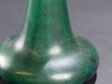 a green vase sitting on a table with a black background