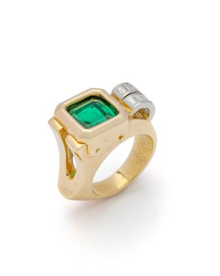 un gros plan d'une bague sertie d'une pierre verte et de deux diamants