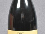 bottle of red wine with a red cap on a grey background