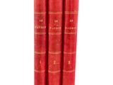 trois livres rouges superposés sur une surface blanche