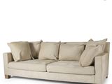 the couch is made of beige fabric and has pillows on top of it