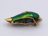 a green and gold beetle sitting on top of a white surface