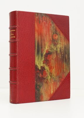 an old book with a red cover sitting on top of a white surface