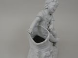 a white statue of a child sitting on a pot