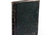 an old book with a green cover on a white surface