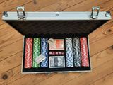 une valise contenant des jetons de poker et des cartes, posée sur un plancher en bois