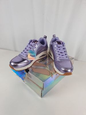 des baskets Puma violettes dans une boîte, sur fond blanc