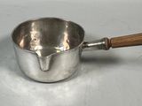 a silver saucepan with a wooden handle on a table