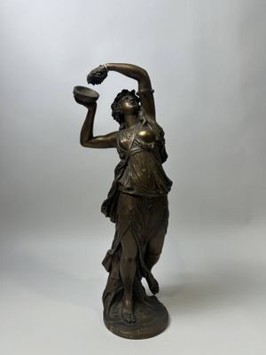 an antique bronze statue of a woman holding a pitcher