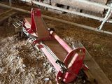 a red sleigh sitting in a barn with hay on the ground