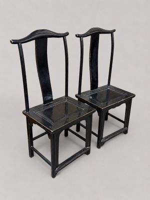 une paire de chaises noires posées sur une surface blanche, sur fond blanc