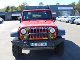 a red jeep parked in a parking lot with other cars