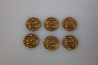 six souverains d'or sont disposés en rangée sur une surface blanche