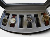 five watches in a case on a white surface