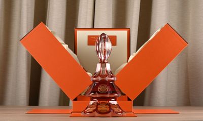 une sculpture en verre orange posée sur une table, à côté d'une boîte