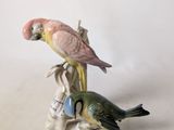 two figurines of parrots sitting on a tree branch