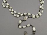 rosary with a silver cross and white beads on a gray background