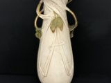 un vase blanc orné d'un motif de feuilles vertes