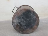 a rusted pot sitting on the floor in front of a white wall