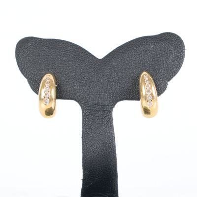 pair of gold and diamond earrings on display on black stand